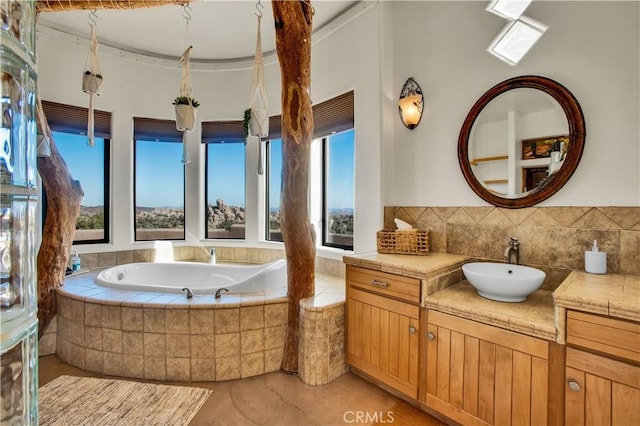 bathroom with tile patterned flooring, tiled tub, and vanity