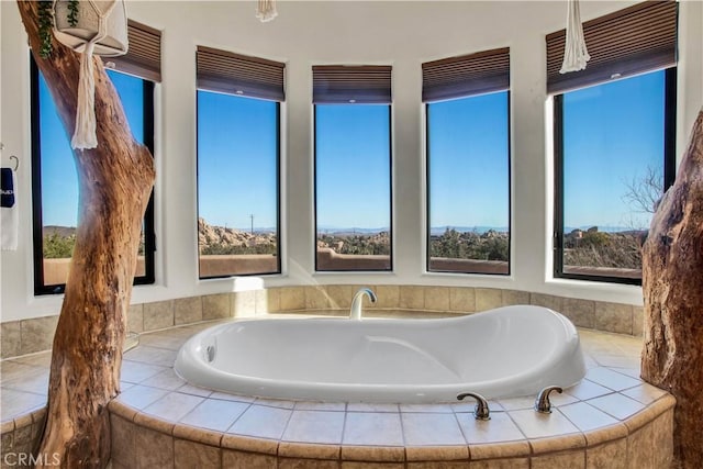 bathroom with a healthy amount of sunlight and a relaxing tiled tub