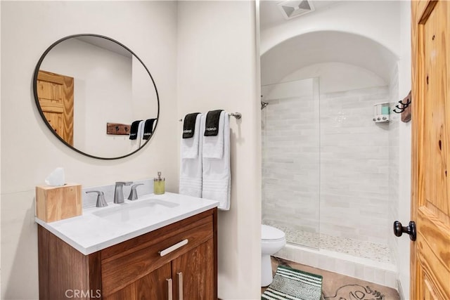 bathroom featuring toilet, vanity, and tiled shower