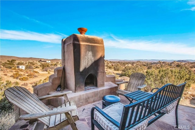 view of patio featuring a mountain view and exterior fireplace