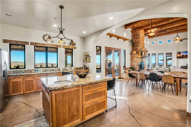 kitchen with concrete flooring, sink, hanging light fixtures, and an island with sink