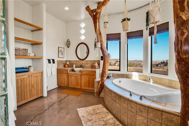 bathroom with vanity, built in features, a relaxing tiled tub, and concrete floors