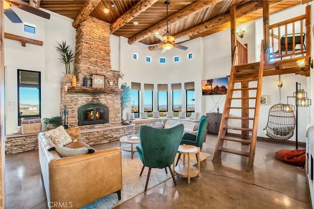 living room with a high ceiling, a fireplace, wooden ceiling, beam ceiling, and concrete flooring