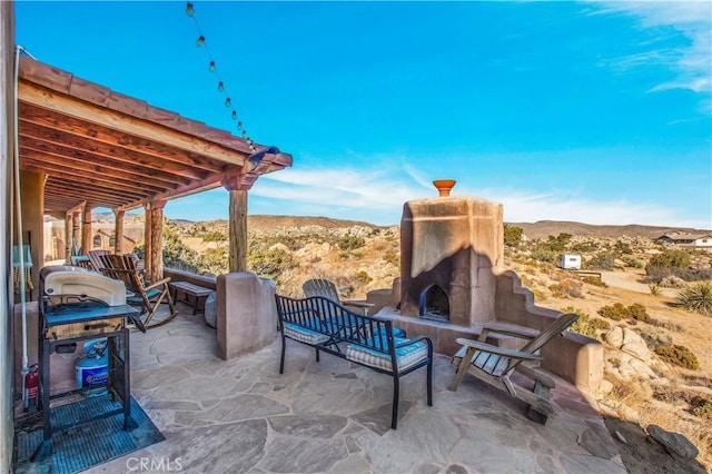 view of patio / terrace with a mountain view and exterior fireplace