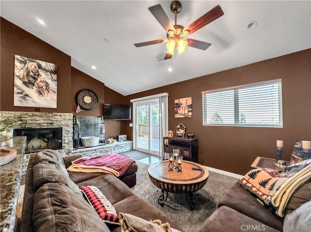 living room featuring ceiling fan, lofted ceiling, and a stone fireplace