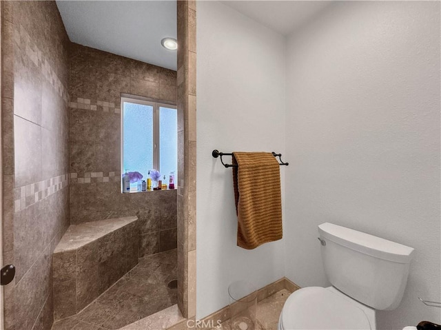 bathroom featuring toilet and tiled shower