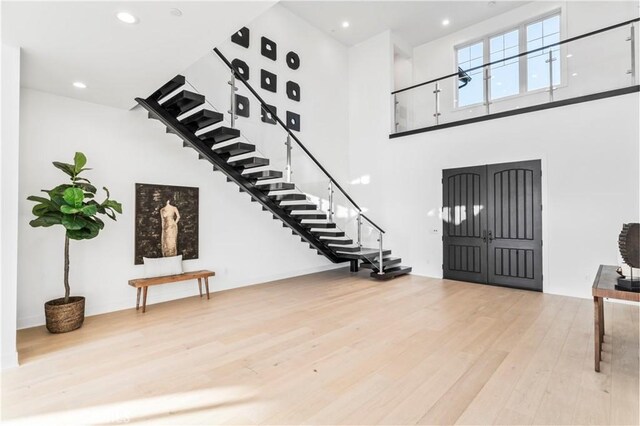 entryway with a towering ceiling and light hardwood / wood-style flooring