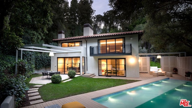 back of property featuring a patio area, a yard, an outdoor hangout area, a fenced in pool, and a balcony