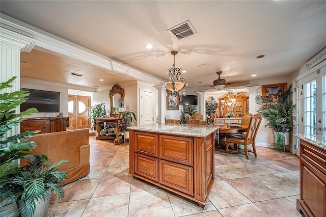 kitchen featuring ornamental molding, a center island, light stone counters, and decorative light fixtures