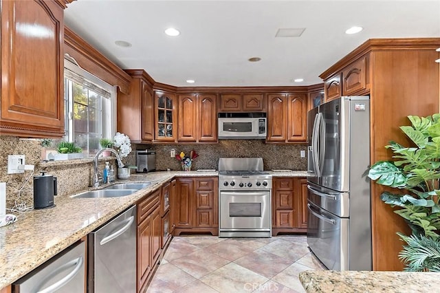 kitchen featuring decorative backsplash, sink, appliances with stainless steel finishes, light tile patterned floors, and light stone counters