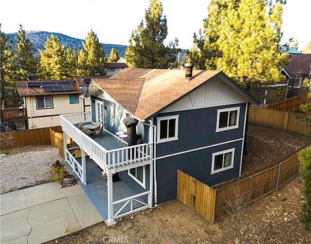 rear view of property with a patio, solar panels, and a deck with mountain view