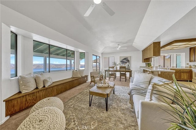 living room with ceiling fan, lofted ceiling, a water view, and light colored carpet