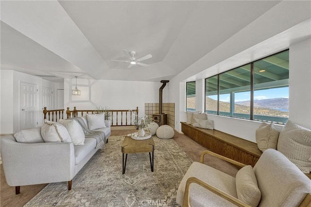 living room with a water view, light colored carpet, ceiling fan, and a wood stove