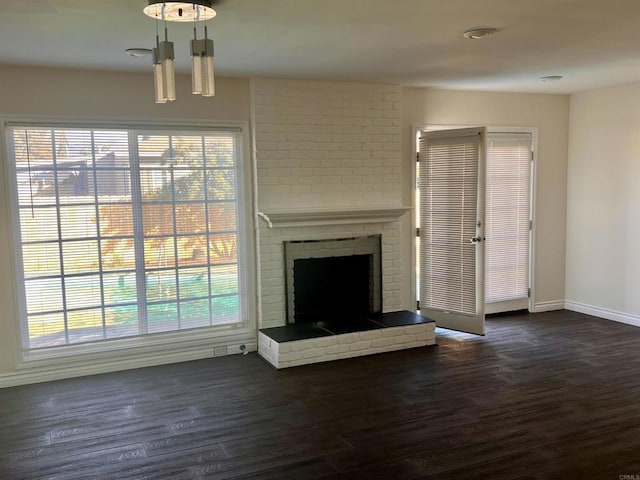 unfurnished living room featuring a brick fireplace and dark hardwood / wood-style flooring