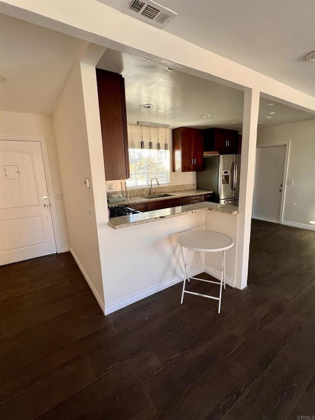 kitchen with sink, kitchen peninsula, dark hardwood / wood-style flooring, and stainless steel fridge with ice dispenser