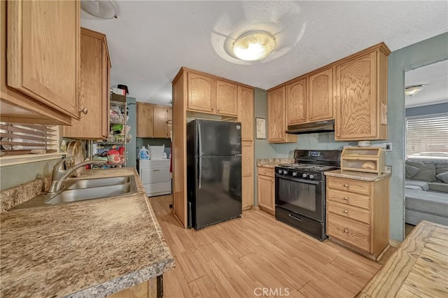 kitchen with washing machine and dryer, light wood-type flooring, a textured ceiling, black appliances, and sink