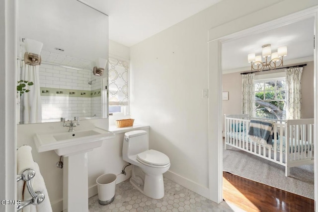 bathroom featuring toilet, sink, a chandelier, and a tile shower