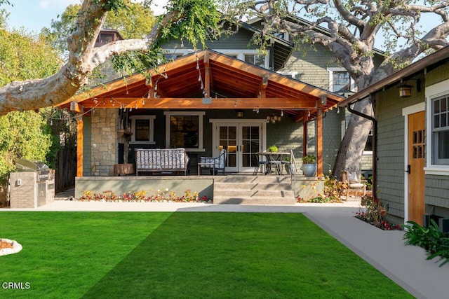 rear view of house featuring exterior kitchen, a patio area, a yard, and french doors