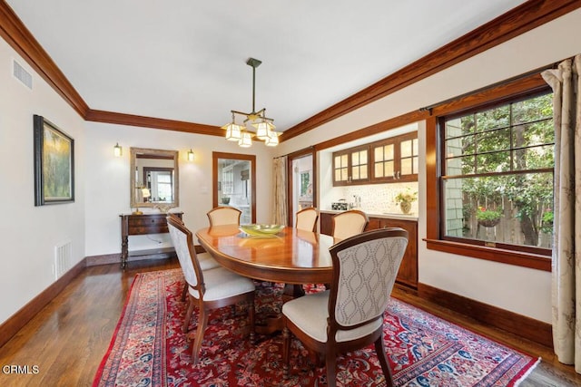 dining room with dark hardwood / wood-style flooring, crown molding, and a chandelier