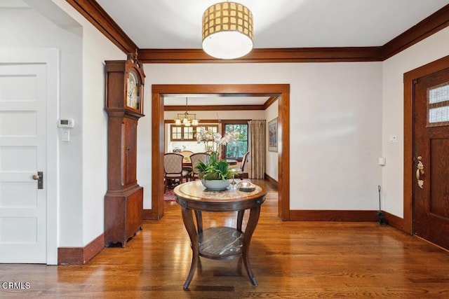 foyer with an inviting chandelier, ornamental molding, and wood-type flooring