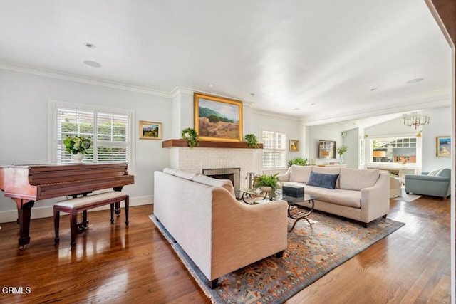 living room with a fireplace, plenty of natural light, a chandelier, and hardwood / wood-style flooring