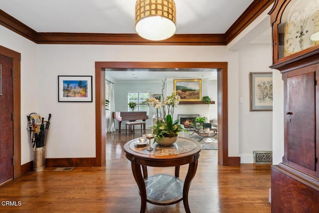 entryway with dark hardwood / wood-style flooring, ornamental molding, and a brick fireplace