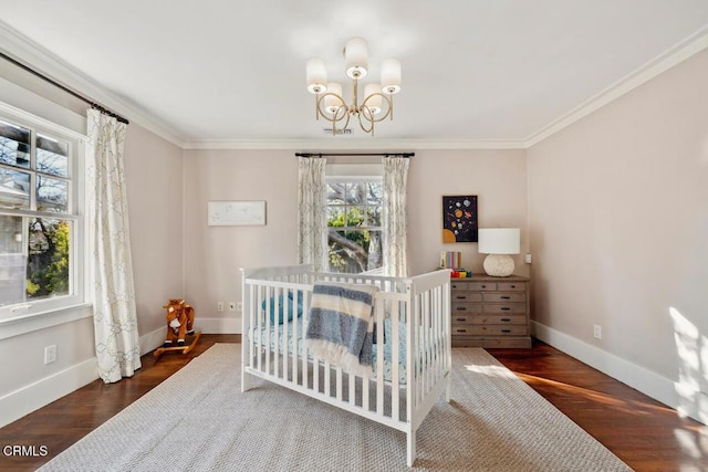 bedroom with a crib, dark hardwood / wood-style floors, an inviting chandelier, and ornamental molding