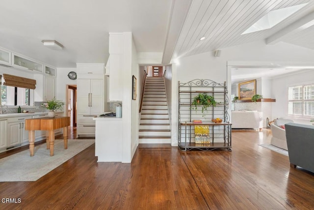 interior space featuring vaulted ceiling with skylight and dark hardwood / wood-style floors