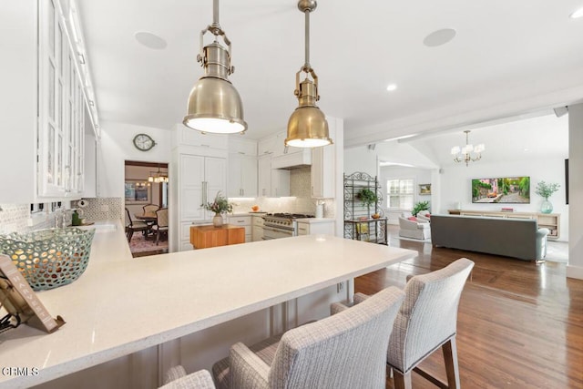 kitchen with hanging light fixtures, a breakfast bar, kitchen peninsula, and decorative backsplash