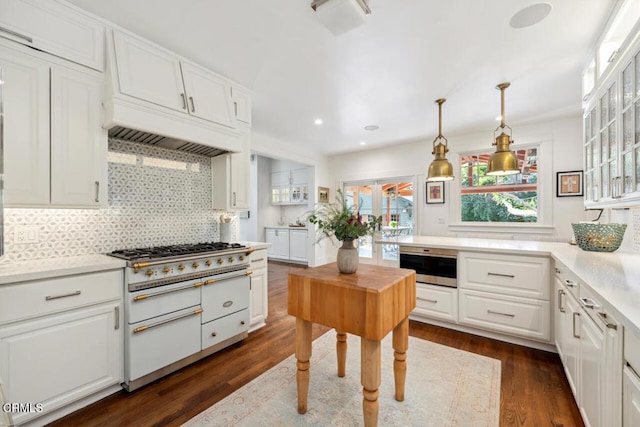 kitchen featuring double oven range, white cabinetry, backsplash, dark hardwood / wood-style floors, and decorative light fixtures