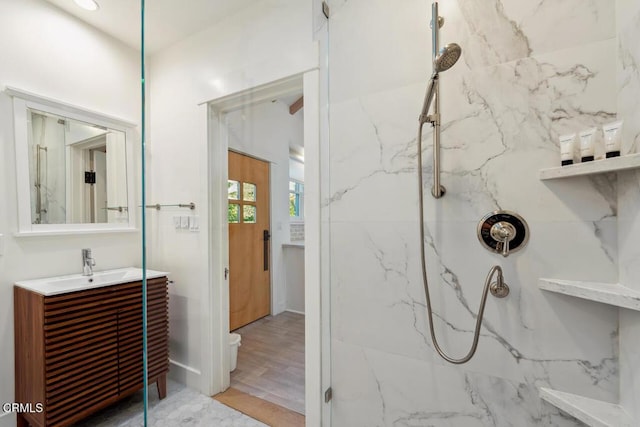 bathroom featuring hardwood / wood-style floors, vanity, and a tile shower