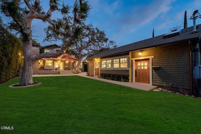 back house at dusk featuring a yard