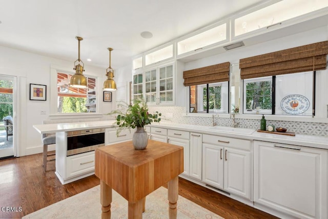 kitchen with sink, a kitchen island, white cabinetry, and pendant lighting