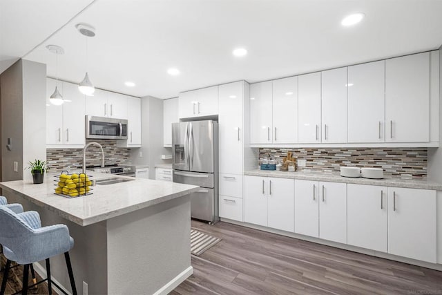 kitchen with decorative light fixtures, kitchen peninsula, sink, white cabinetry, and appliances with stainless steel finishes