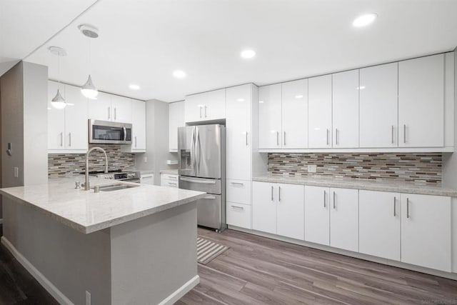 kitchen with kitchen peninsula, sink, white cabinetry, hanging light fixtures, and appliances with stainless steel finishes