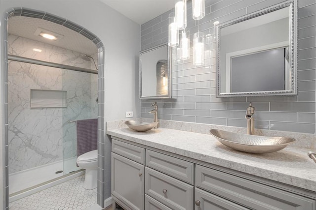 bathroom featuring tile patterned flooring, a shower with door, vanity, tasteful backsplash, and toilet