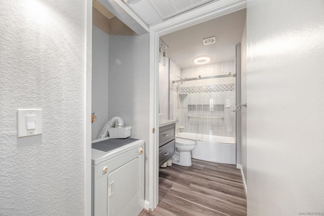 bathroom featuring toilet, washer / clothes dryer, tiled shower / bath, and hardwood / wood-style flooring