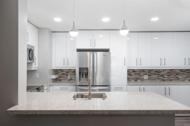 kitchen with hanging light fixtures, white cabinets, decorative backsplash, and appliances with stainless steel finishes