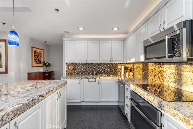 kitchen featuring white cabinetry, decorative backsplash, sink, pendant lighting, and stainless steel appliances