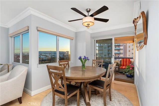 dining space featuring crown molding, light wood-type flooring, ceiling fan, and plenty of natural light