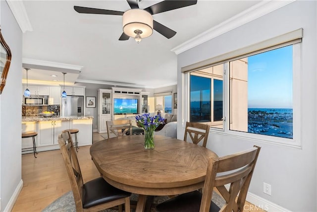 dining space featuring light wood-type flooring, ceiling fan, and ornamental molding