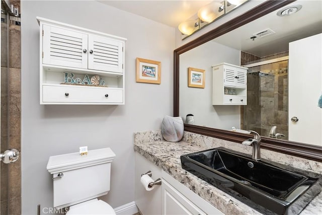 bathroom with toilet, vanity, and a tile shower