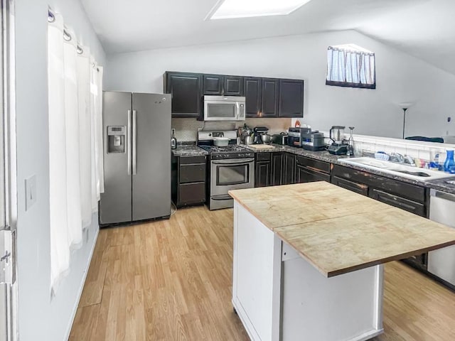 kitchen featuring lofted ceiling, sink, a breakfast bar, stainless steel appliances, and light hardwood / wood-style floors