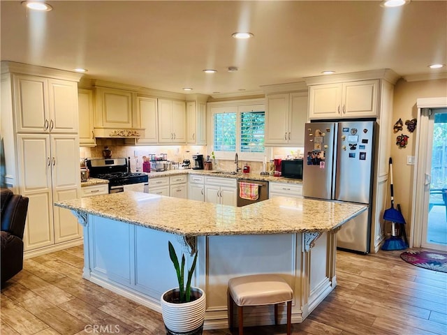 kitchen with stainless steel appliances, a breakfast bar, a sink, and light wood-style floors