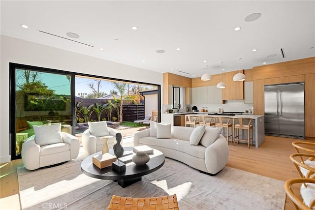 living room with a wealth of natural light, light hardwood / wood-style flooring, and sink