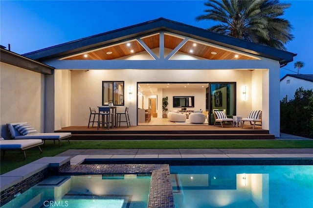 rear view of property featuring a pool with hot tub and an outdoor hangout area