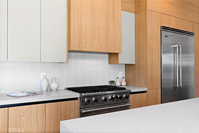 kitchen featuring white cabinets, decorative backsplash, and high quality appliances