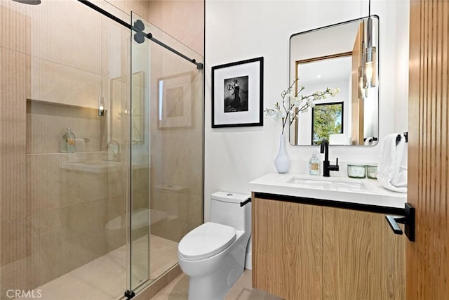 bathroom featuring a shower with door, toilet, and vanity