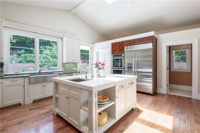 kitchen featuring stainless steel appliances, sink, white cabinets, and a kitchen island with sink