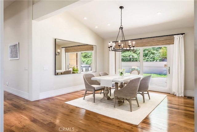 dining area featuring hardwood / wood-style flooring, an inviting chandelier, and vaulted ceiling